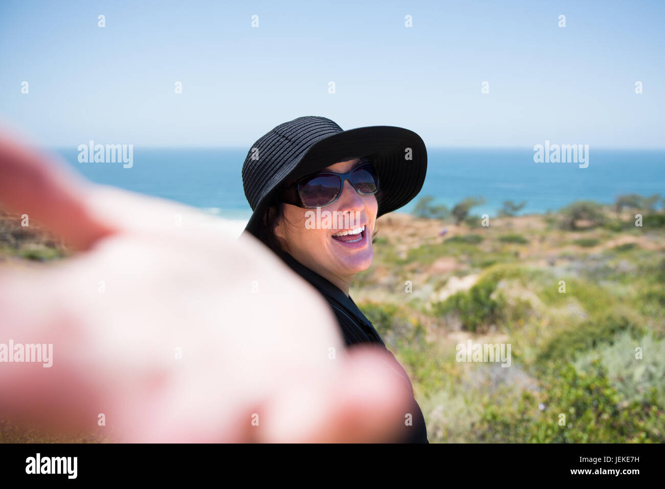 Frau am Strand mit ihrem Arm ausgestreckt, ihr zu folgen Stockfoto