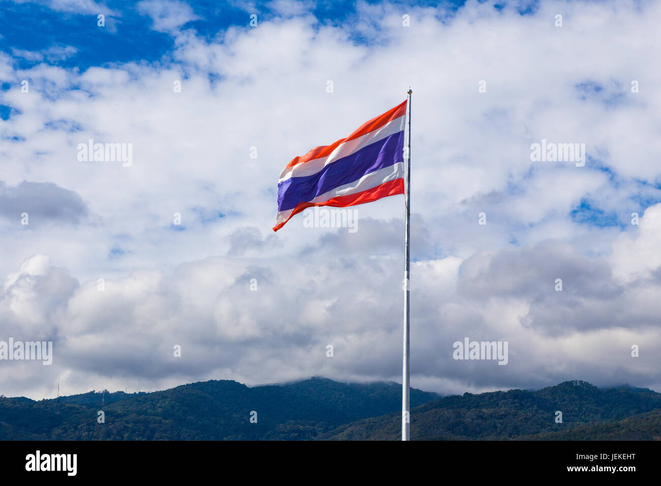 Thai national Flagge auf ihrem Pol an einem sonnigen Tag, mit Blick auf Berge und bewölkten blauen Himmelshintergrund Stockfoto