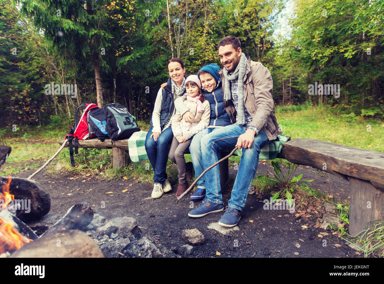 Glückliche Familie sitzt auf der Bank am Lagerfeuer. Stockfoto