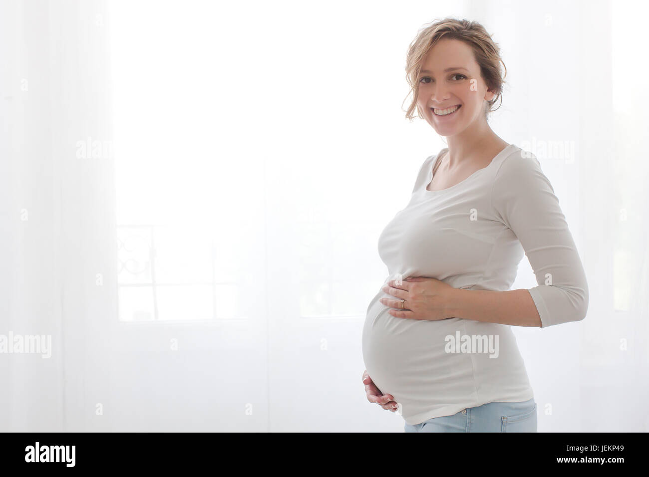 Schwangere Frau berühren Bauch an Kamera suchen auf weißem Hintergrund Stockfoto
