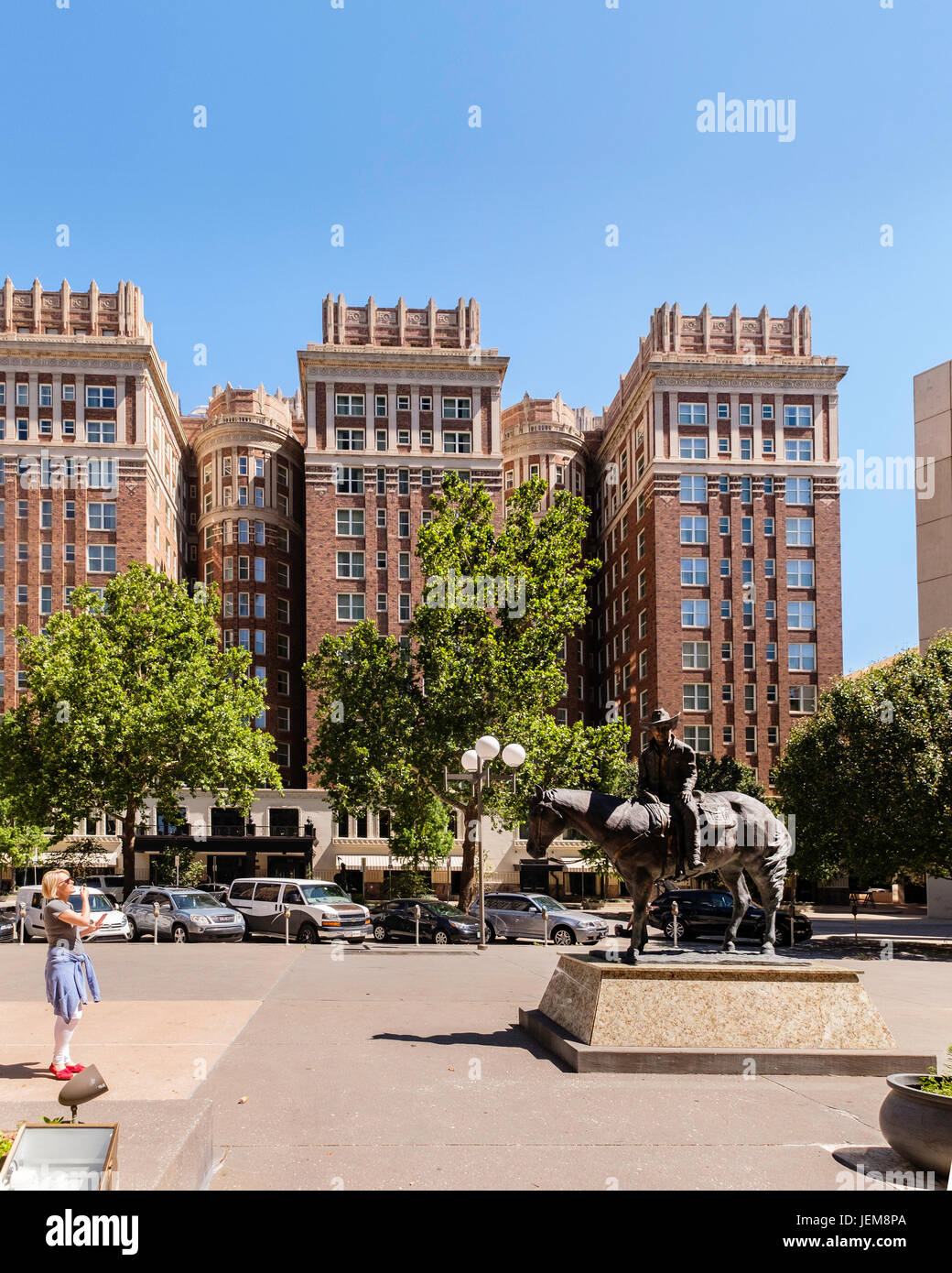 Historisches Skirvin Hilton-Hotel in der Innenstadt von Oklahoma City, OK, USA, gebaut 1910 komplett mit einem Geist. Cotter Ranch Turm Cowboy Skulptur im Vordergrund. Stockfoto