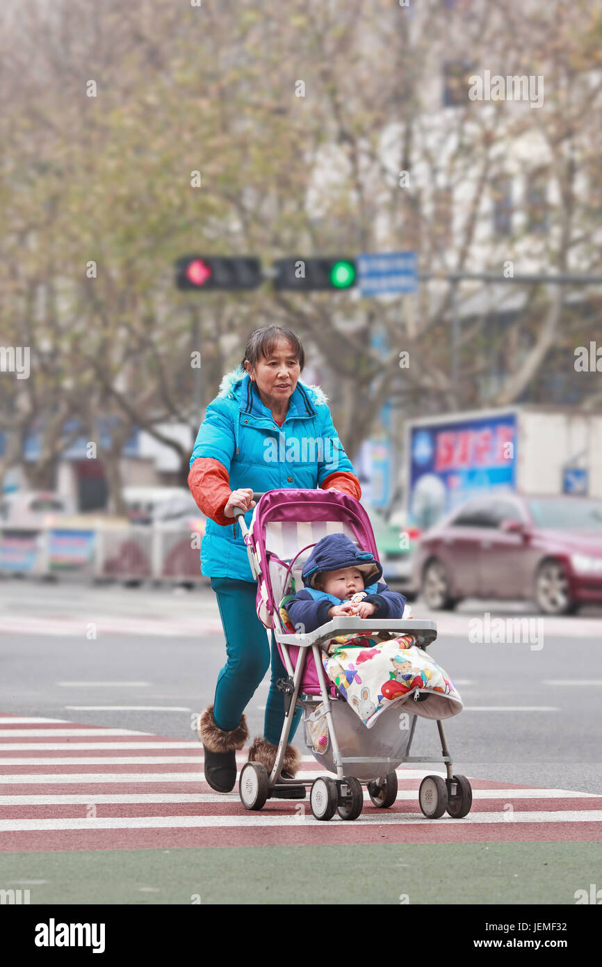 Elder mit Enkel in Baby Auto. Ihren Kindern zu helfen, berufliche Ziele, Chinesisch ältere Menschen oft eine aktive Rolle dabei spielen, indem sie den Enkelkindern zu verfolgen. Stockfoto