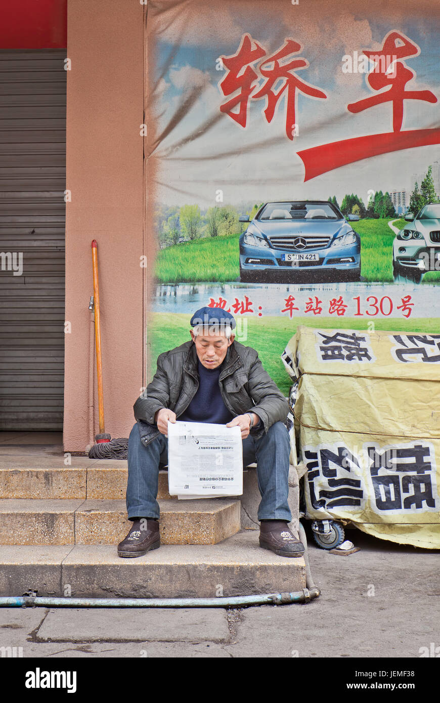 Chinesischer Mann liest Zeitung. Chinesische Zeichen Nummer in die Zehntausende. Das Lesen von Zeitungen erfordert Wissen über 3000 Zeichen. Stockfoto