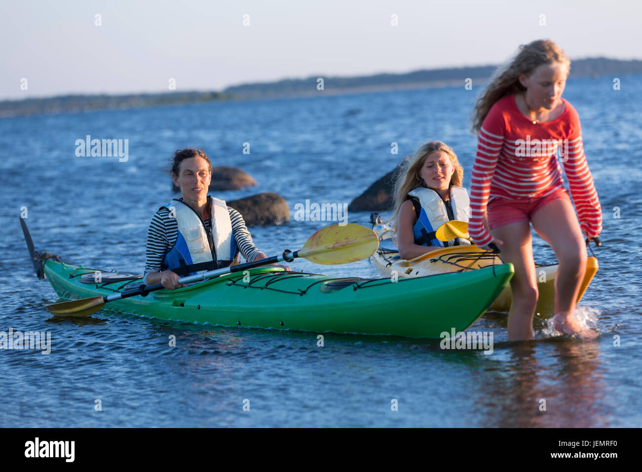 Mädchen ziehen Kajaks im Meer Stockfoto