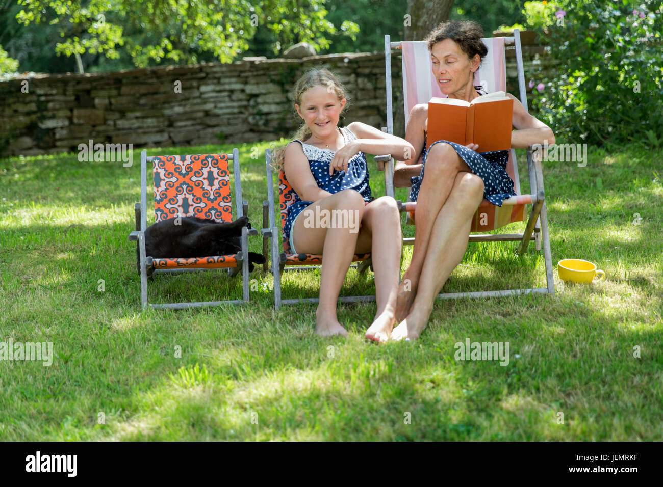 Reife Frau mit Tochter und Katze im Garten Stockfoto