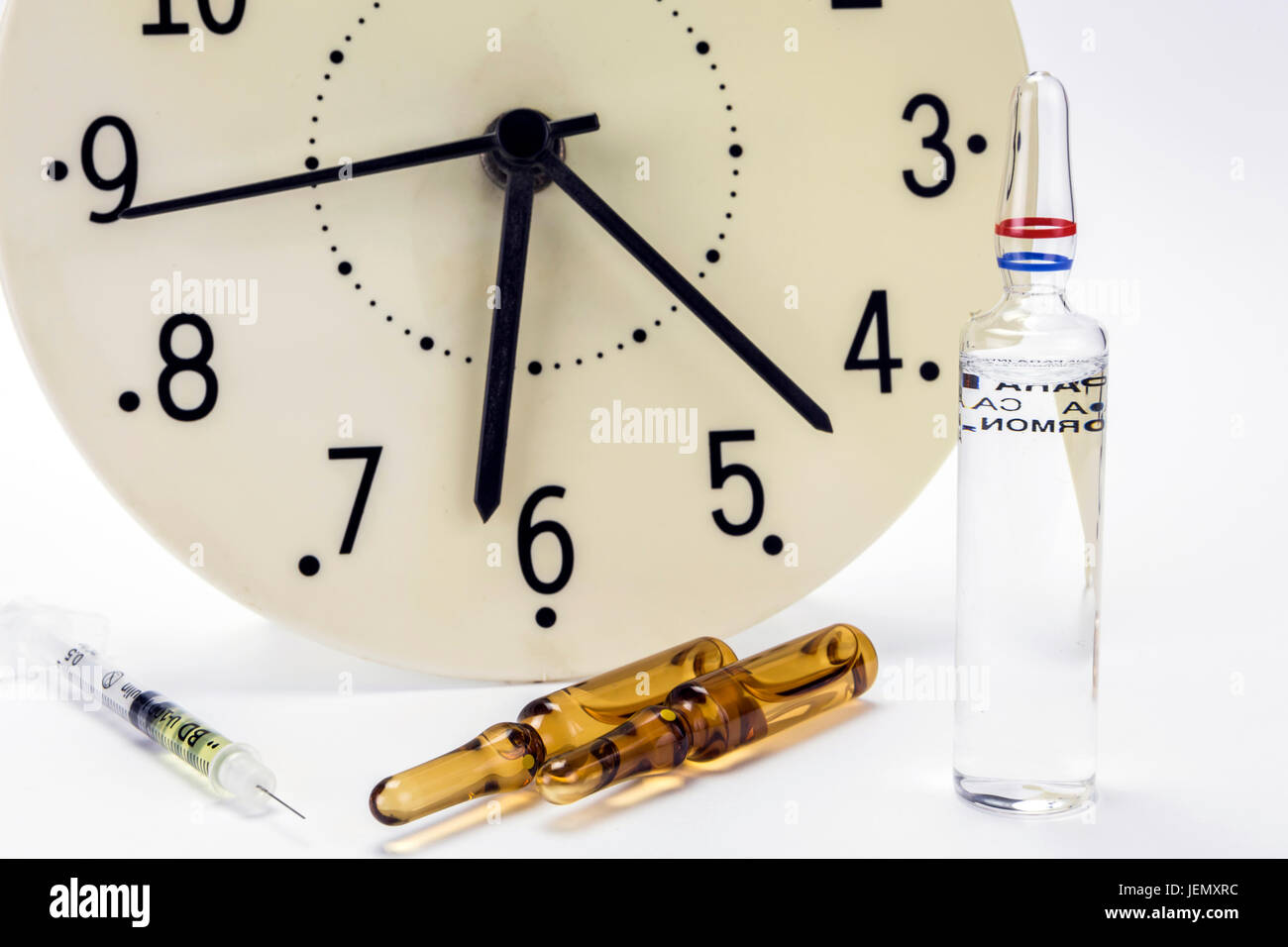 Medizin-Fläschchen und Spritze, die Uhr zeigt die Zeit der Medikation Stockfoto