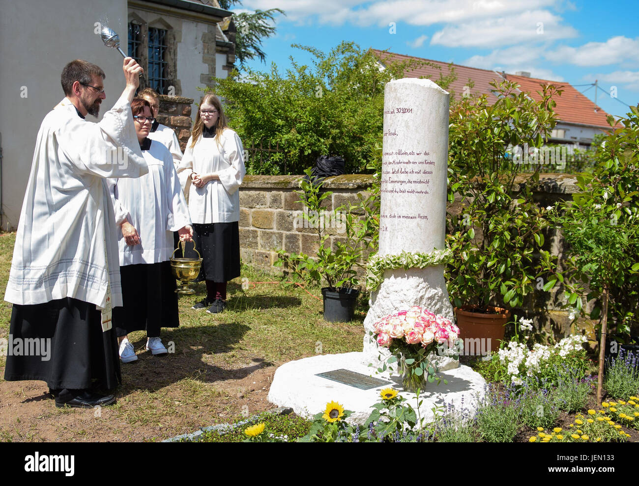 Pfarrer Heinz-Georg Müller segnet ein Denkmal zu Ehren von Pascal, ein Kind, das vor 16 Jahren auf dem katholischen Friedhof in Schwalbach, Deutschland, 24. Juni 2017 vermisst. Foto: Oliver Dietze/dpa Stockfoto