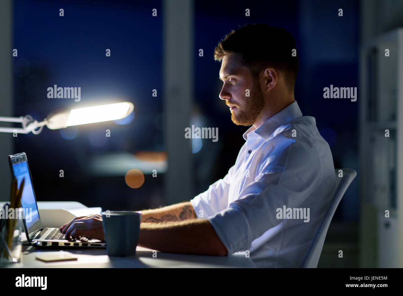 Mann mit Laptop und arbeiten bei Nachtgottesdienst Kaffee Stockfoto