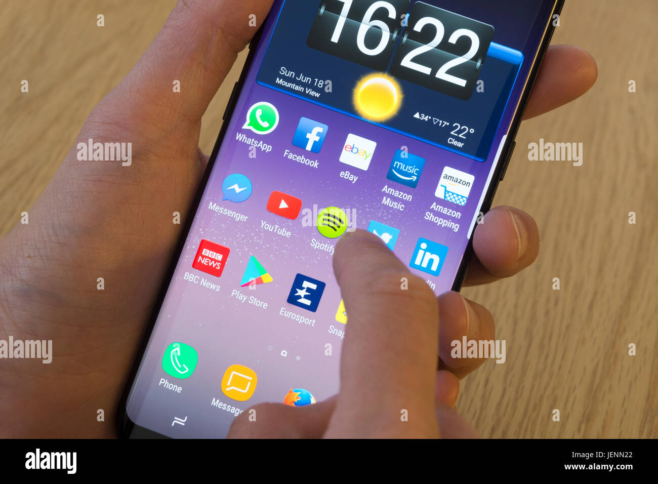 Eine junge Frau, die Auswahl der Spotify-app auf dem smartphone Stockfoto
