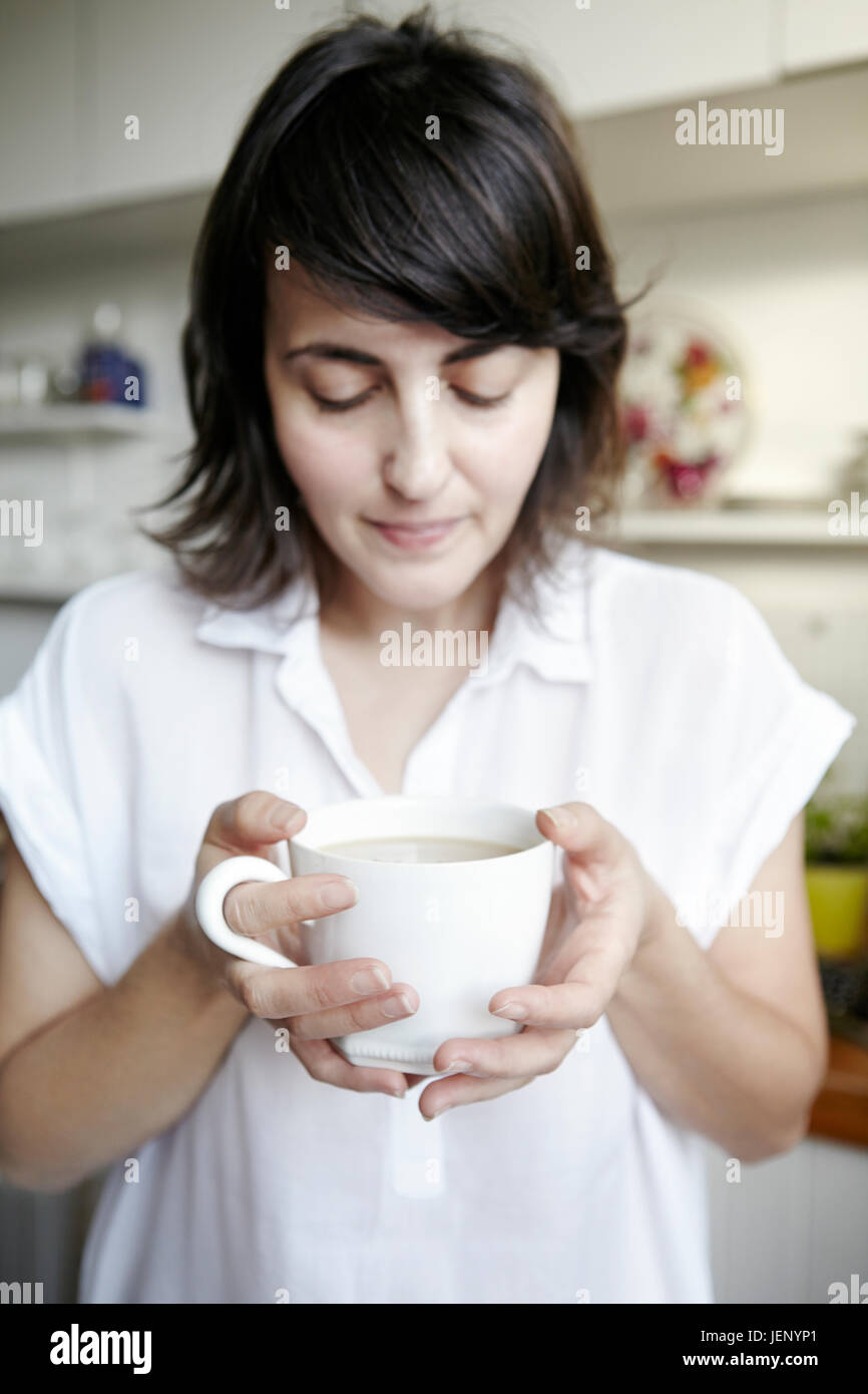 Junge Frau mit Becher mit Heißgetränk Stockfoto