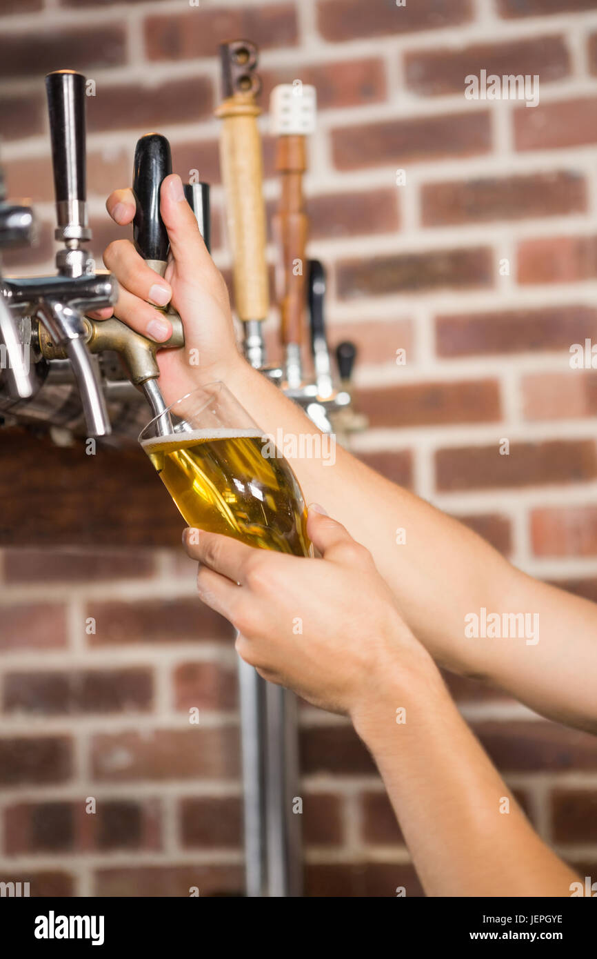 Gut aussehend Barkeeper einen Pint Bier in Strömen Stockfoto