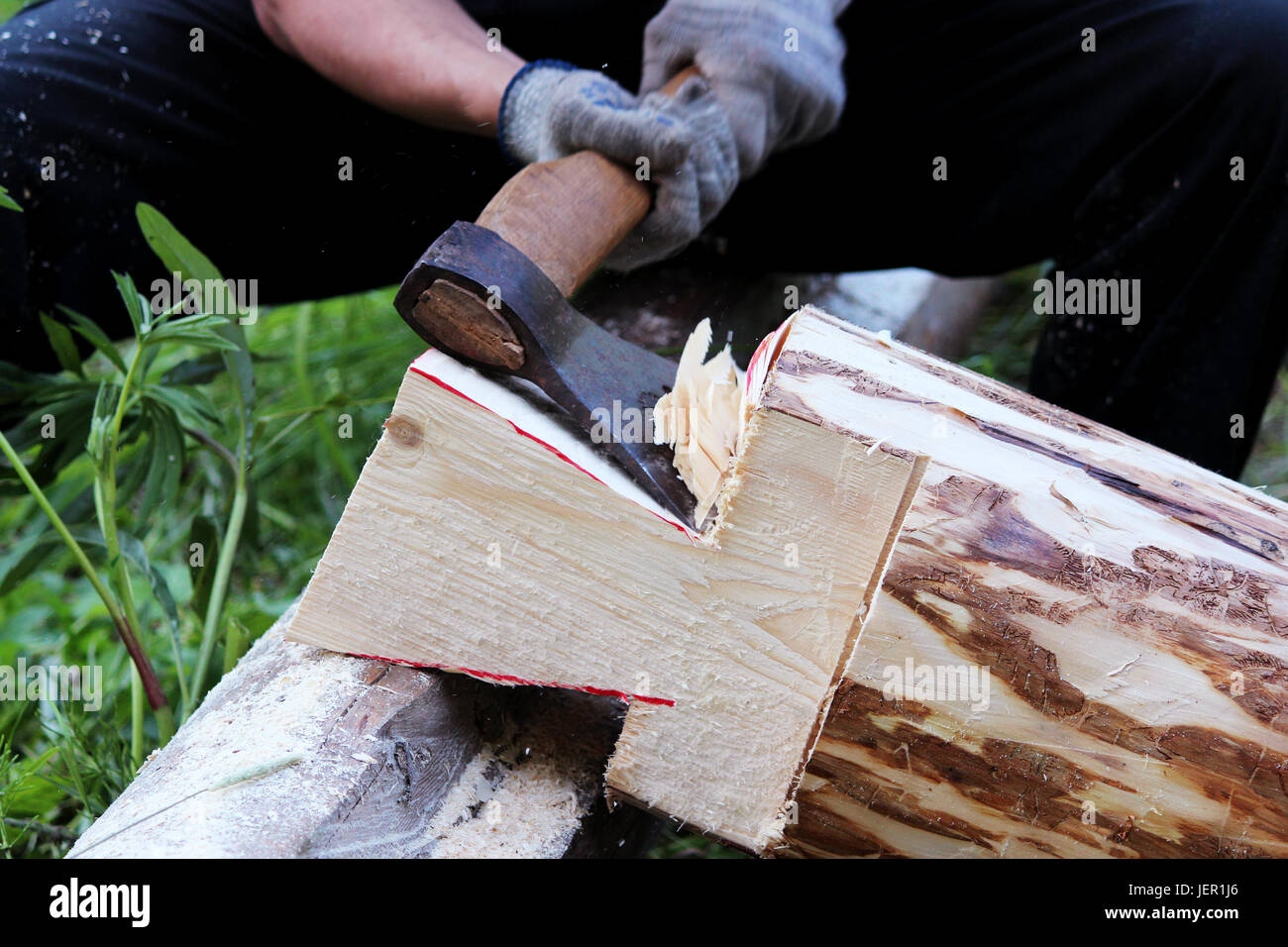 Der Arbeitnehmer erhebt einen Holzrahmen mit Hilfe von einem Hacket beim Bau eines Hauses Stockfoto
