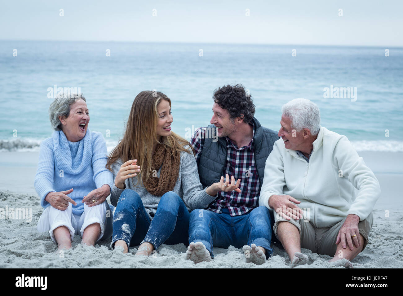 Lächelnde Familie sitzt am Meeresufer Stockfoto