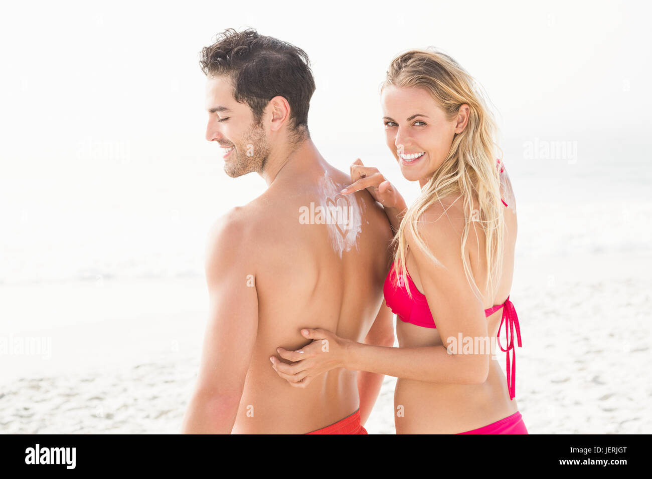 Auftragen von Sonnencreme auf Freund Freundin Stockfoto