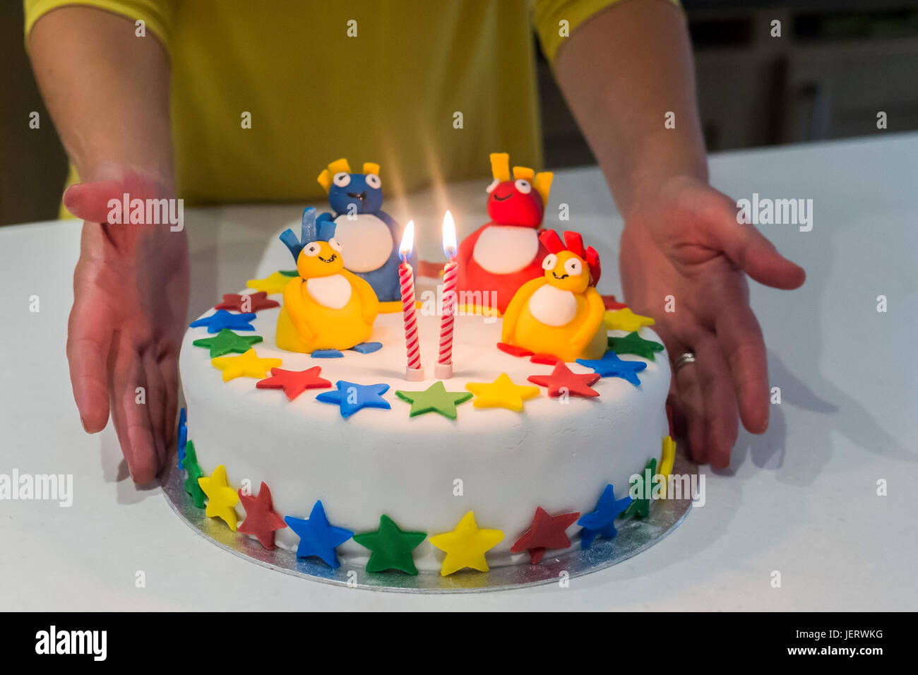 Eine bunte Geburtstagstorte mit zwei brennenden Kerzen. Stockfoto