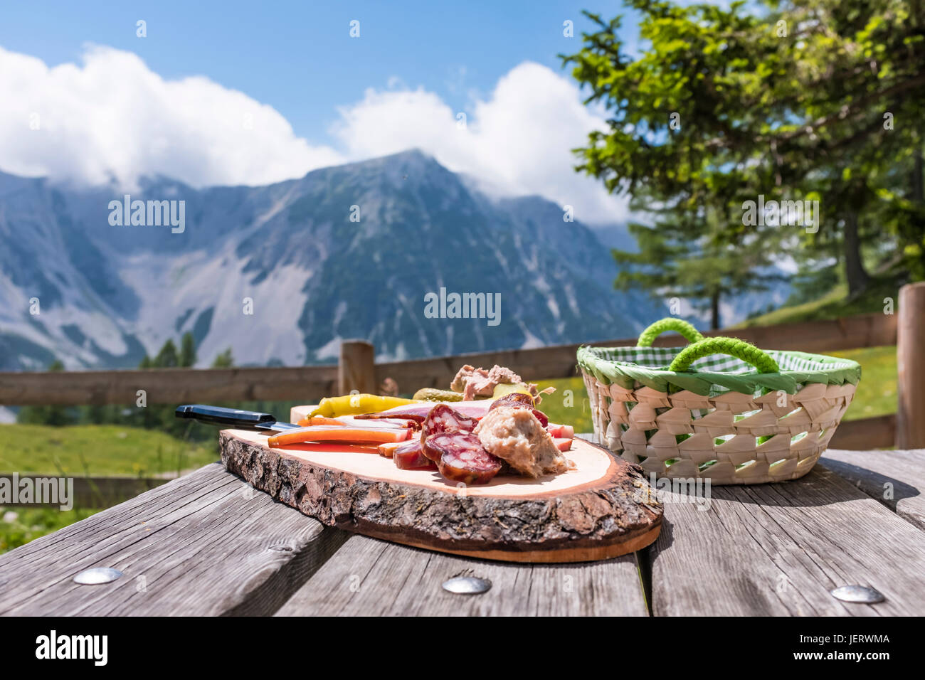 Brettljause auf Holztisch auf Klagenfurter Hütte mit Blick auf Berg Weinasch in den Karawanken Stockfoto
