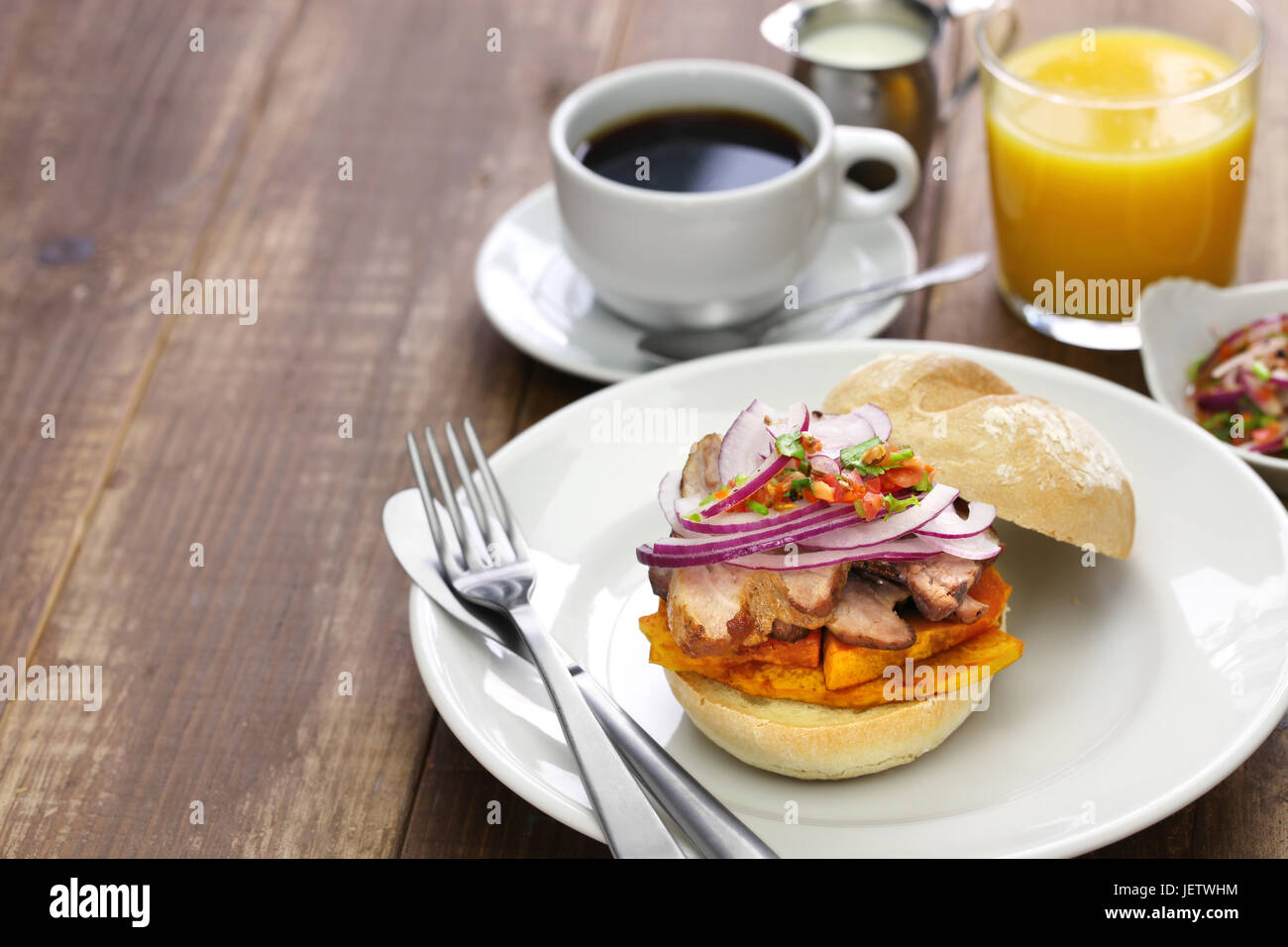 Brötchen mit gebratenem Schweinefleisch, Süßkartoffel und Salsa Criolla. Stockfoto