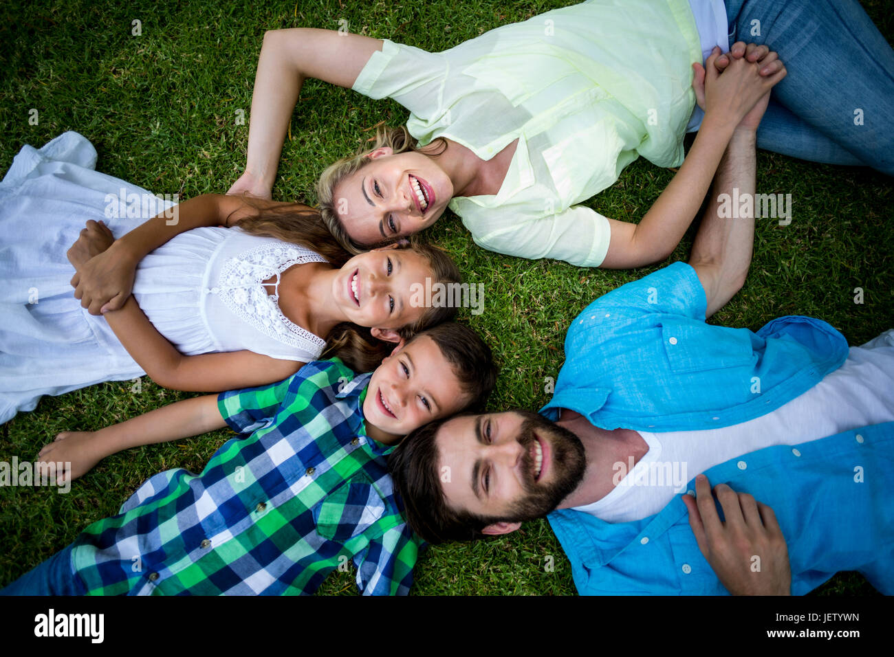 Lächelnde Familie liegen auf dem Rasen im Garten Stockfoto