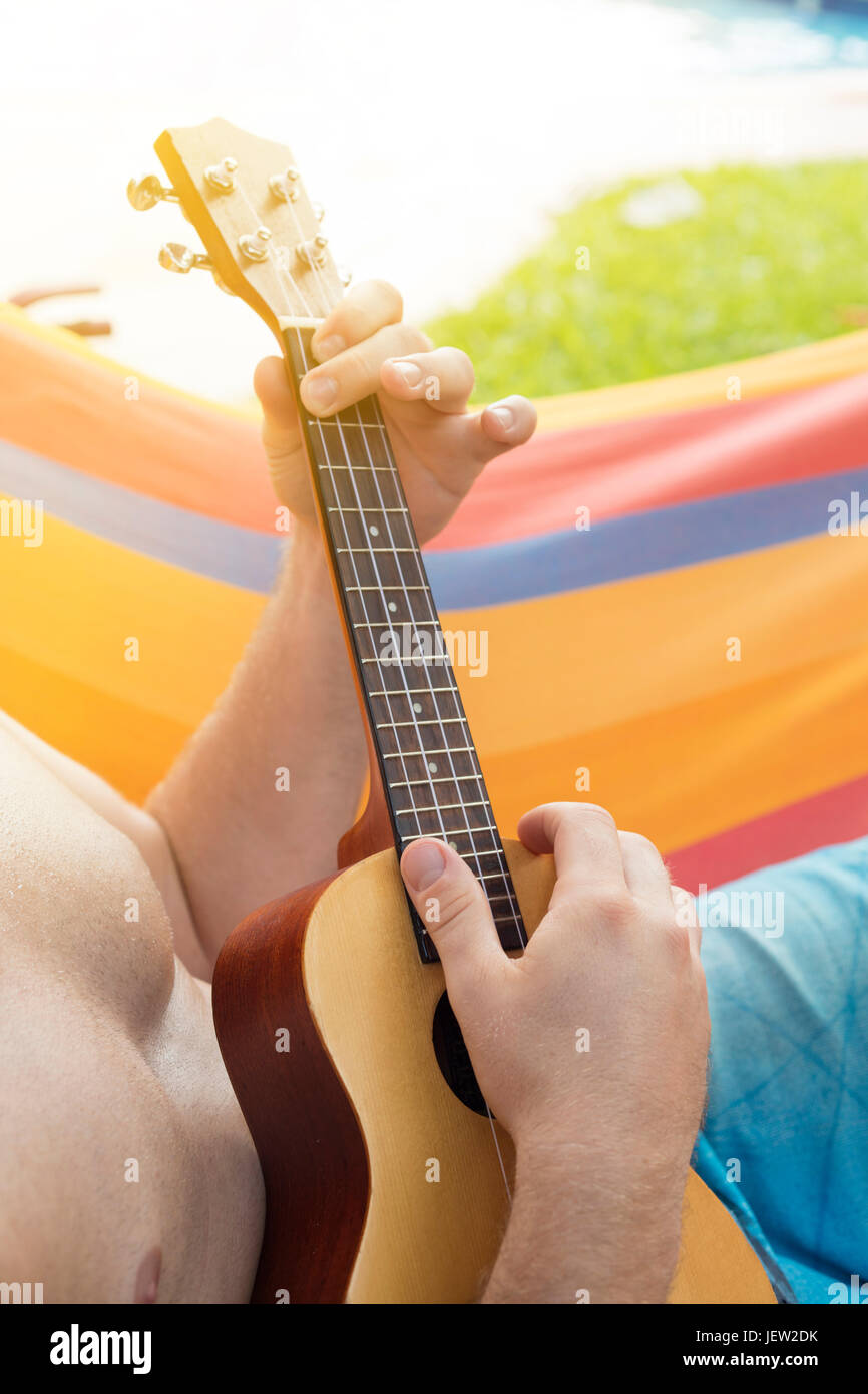 Detail der Mann entspannt auf einer Hängematte und Ukulele zu spielen. Stockfoto