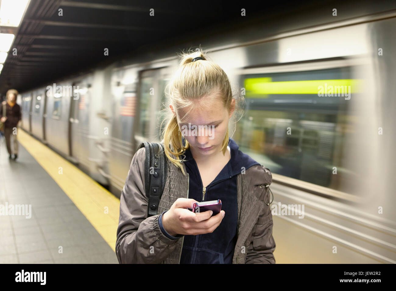 Junge Frau betrachten Smartphone, trainieren Sie auf Hintergrund Stockfoto