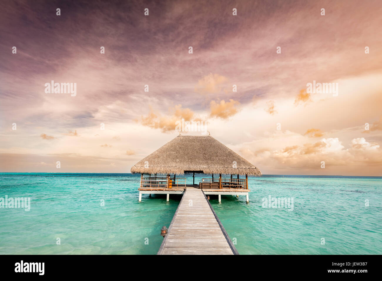 Holzsteg führt zur Entspannung Lodge. Resort auf den Malediven Inseln im Indischen Ozean bei Sonnenaufgang Stockfoto