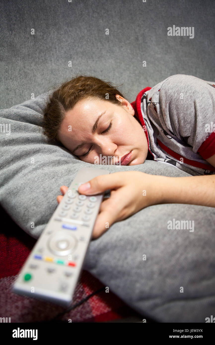 Kaukasische Mädchen schläft auf der Couch mit TV-Fernbedienung in der hand Stockfoto