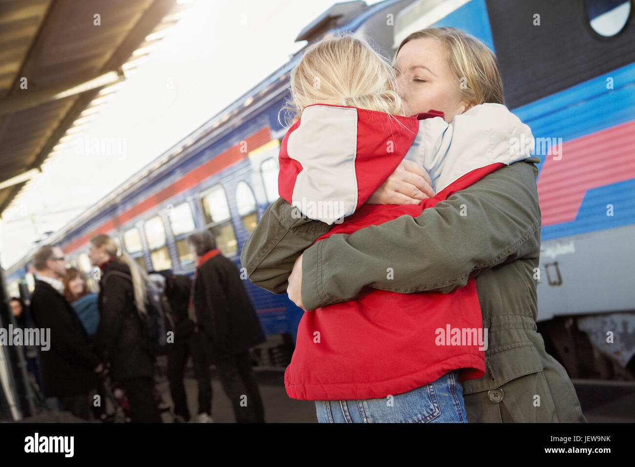Mutter umarmt Tochter am Bahnhof Stockfoto