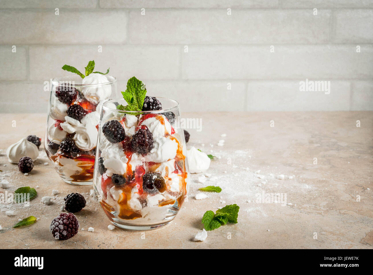 Traditionelle englische Dessert. Eton Mess - Sahne, Baiser, frische Brombeeren, Sauce und Karamell. Gläser auf einem Leuchttisch Stein zu dienen. Co Stockfoto