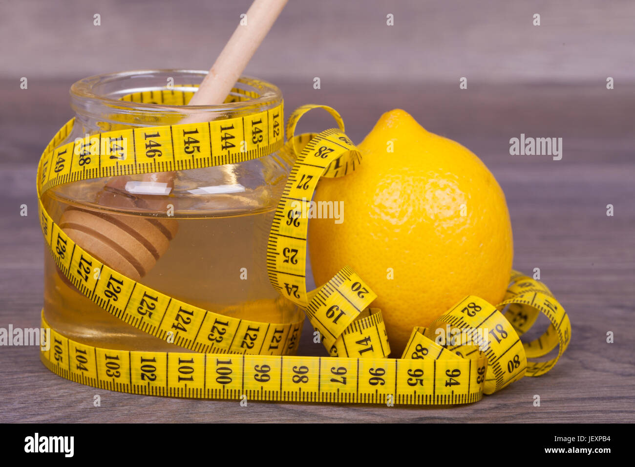 Honig und Zitrone auf einem hölzernen Hintergrund. Die Kombination von Honig und Zitrone dient zur Gewichtsreduktion und zur Stärkung des Immunsystems des Körpers. Stockfoto