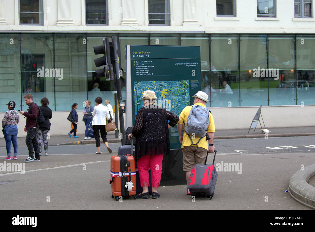 Amerikanische Touristen mit Gepäck auf den Straßen von Glasgow Blick auf Stadtplan Stadtführer Stockfoto