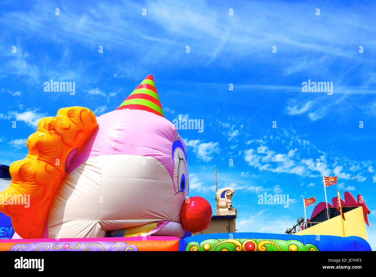 Profil von Clowns Kopf über eine bunte Hüpfburg gegen den blauen Himmel auf Pier Süd", Blackpool, Lancashire, Großbritannien Stockfoto