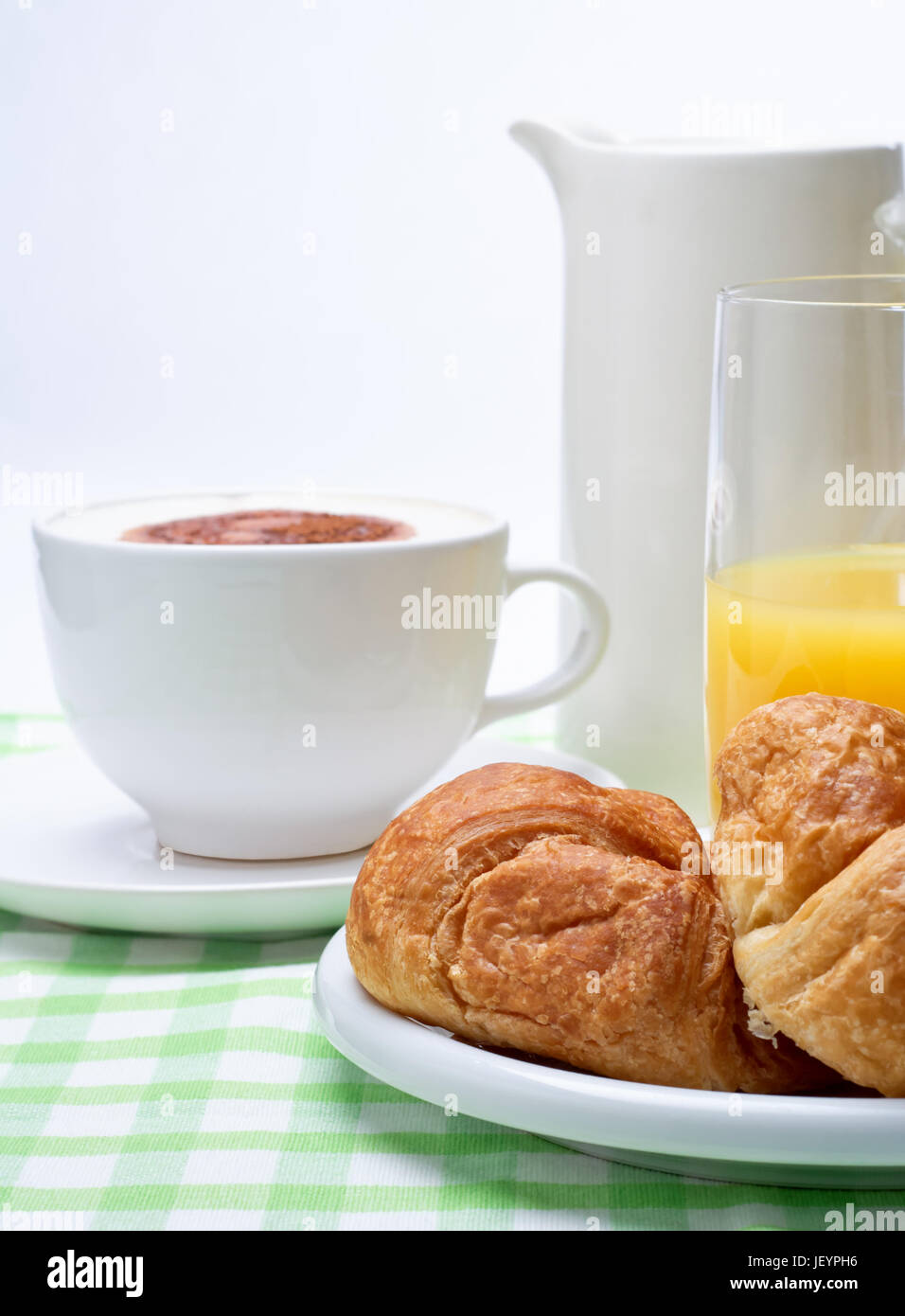Eine Einstellung der Frühstück Croissant, Orangensaft und Kaffee auf einer grünen karierte Tischdecke. Stockfoto