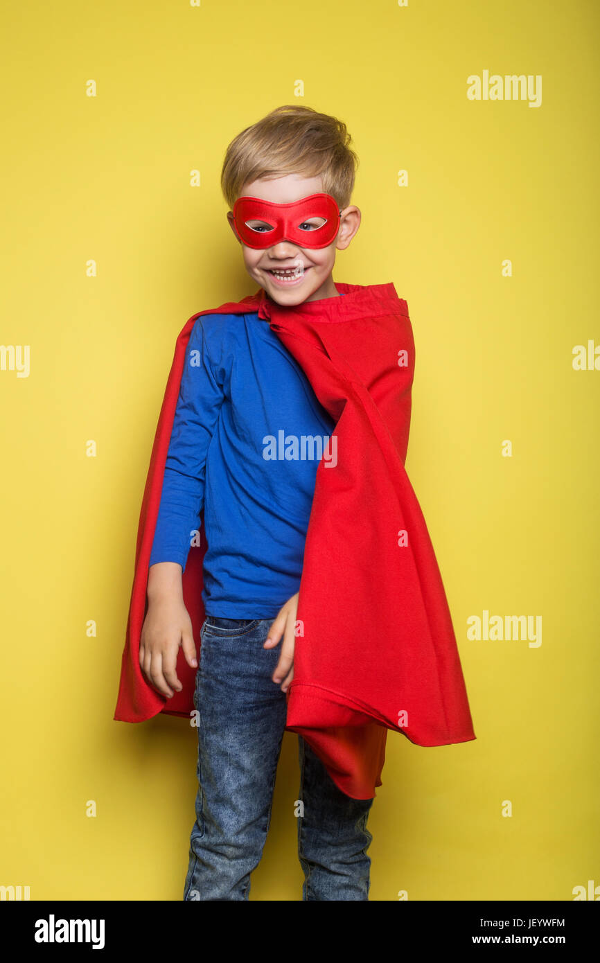 Junge im roten Superhelden Cape und Maske. Superman. Studio-Porträt auf gelbem Hintergrund Stockfoto