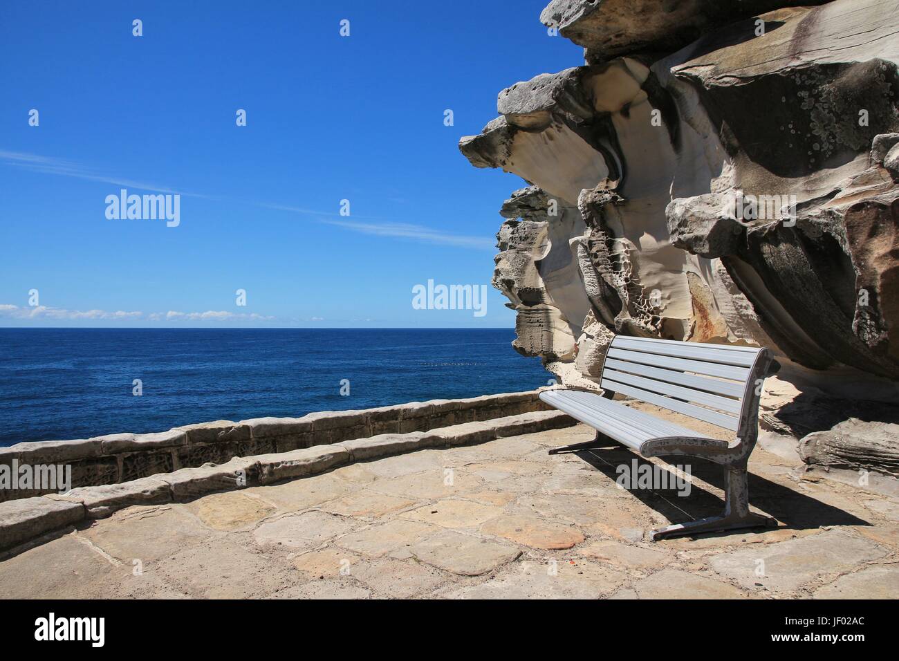 Sitzbank und verwitterter Fels in der Nähe von Bondi Beach Stockfoto