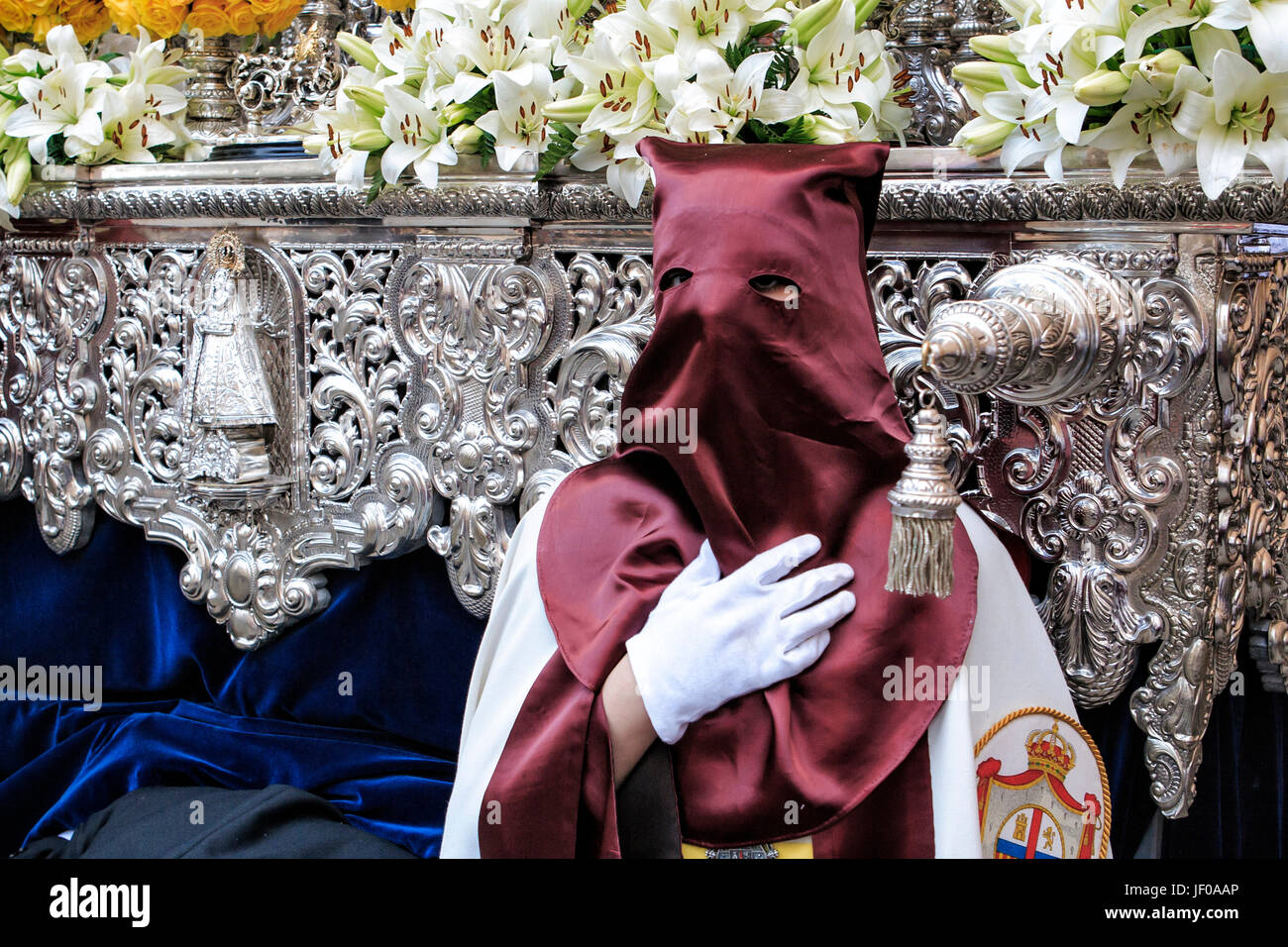Nazarener, die mit der Hand auf der Manigueta den Thron in einer Prozession der Heiligen Woche geht. Nicht tragen Capirote, Sevilla, Andalusien, Spanien Stockfoto
