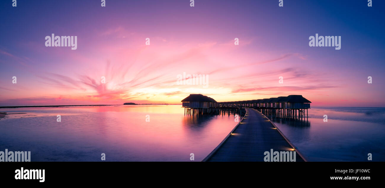 Sonnenuntergang Strand in Malediven, mit luxuriösen über Wasser Villen und perfekten Sonnenuntergang Himmel. Verträumte Sommer und Urlaub Konzept Stockfoto