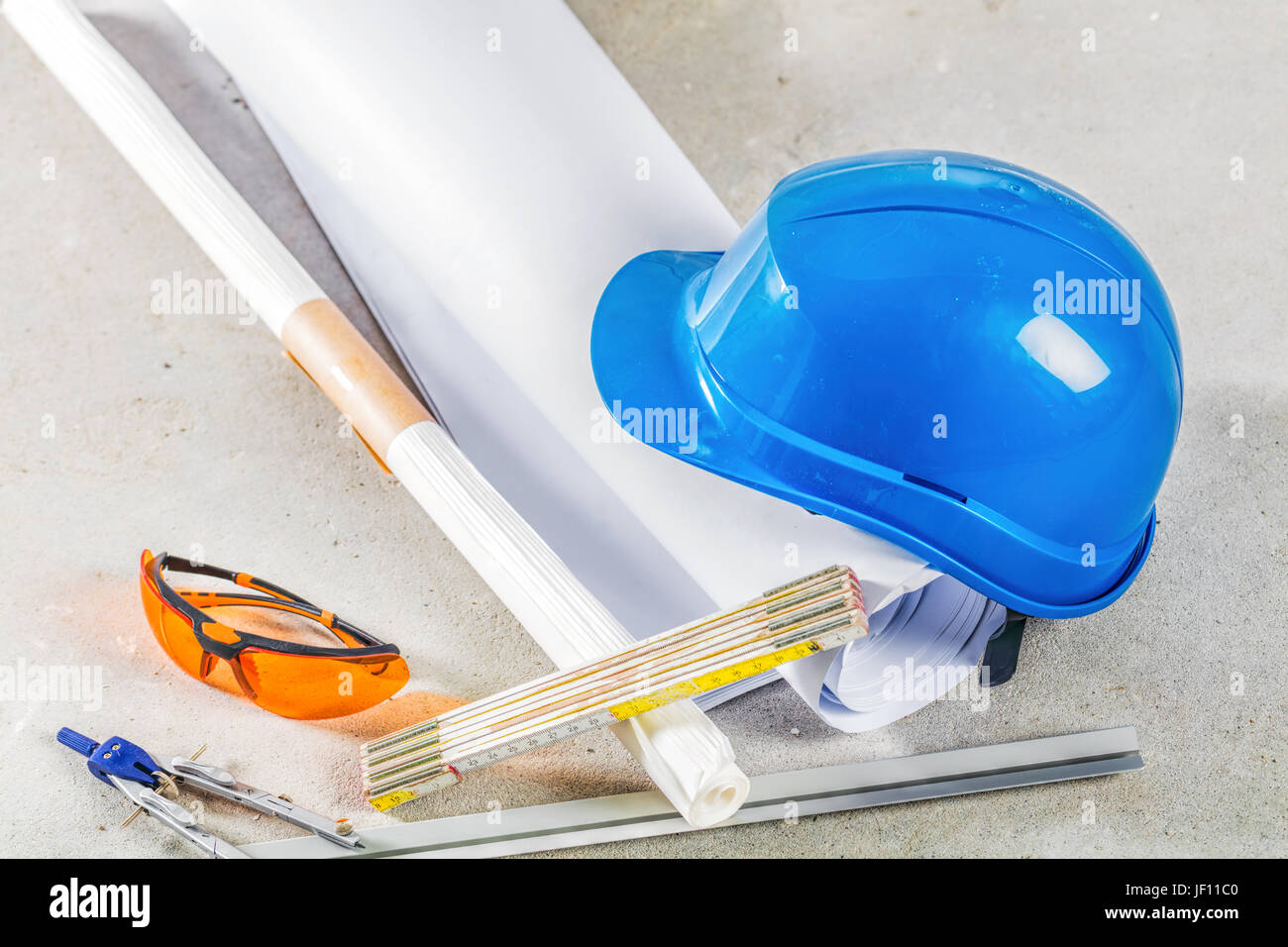 Schutzhelm, Schutzbrille und Baupläne auf der Baustelle. Gebäude und ihre Werkzeuge hautnah. Stockfoto