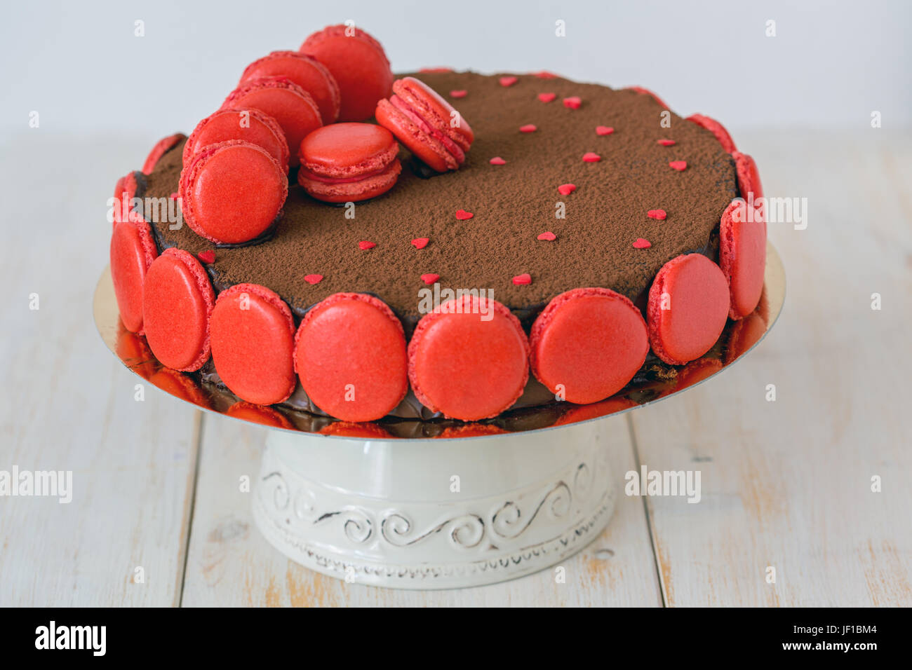 Schokoladenkuchen mit Macarons und roten Herzen verziert. Stockfoto