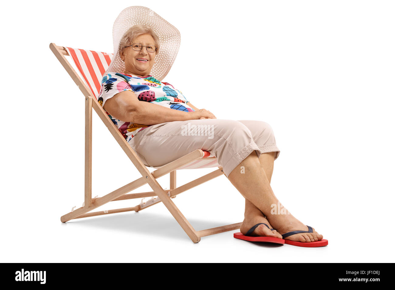 Ältere Frau in einem Liegestuhl sitzen und schaut in die Kamera, die isoliert auf weißem Hintergrund Stockfoto