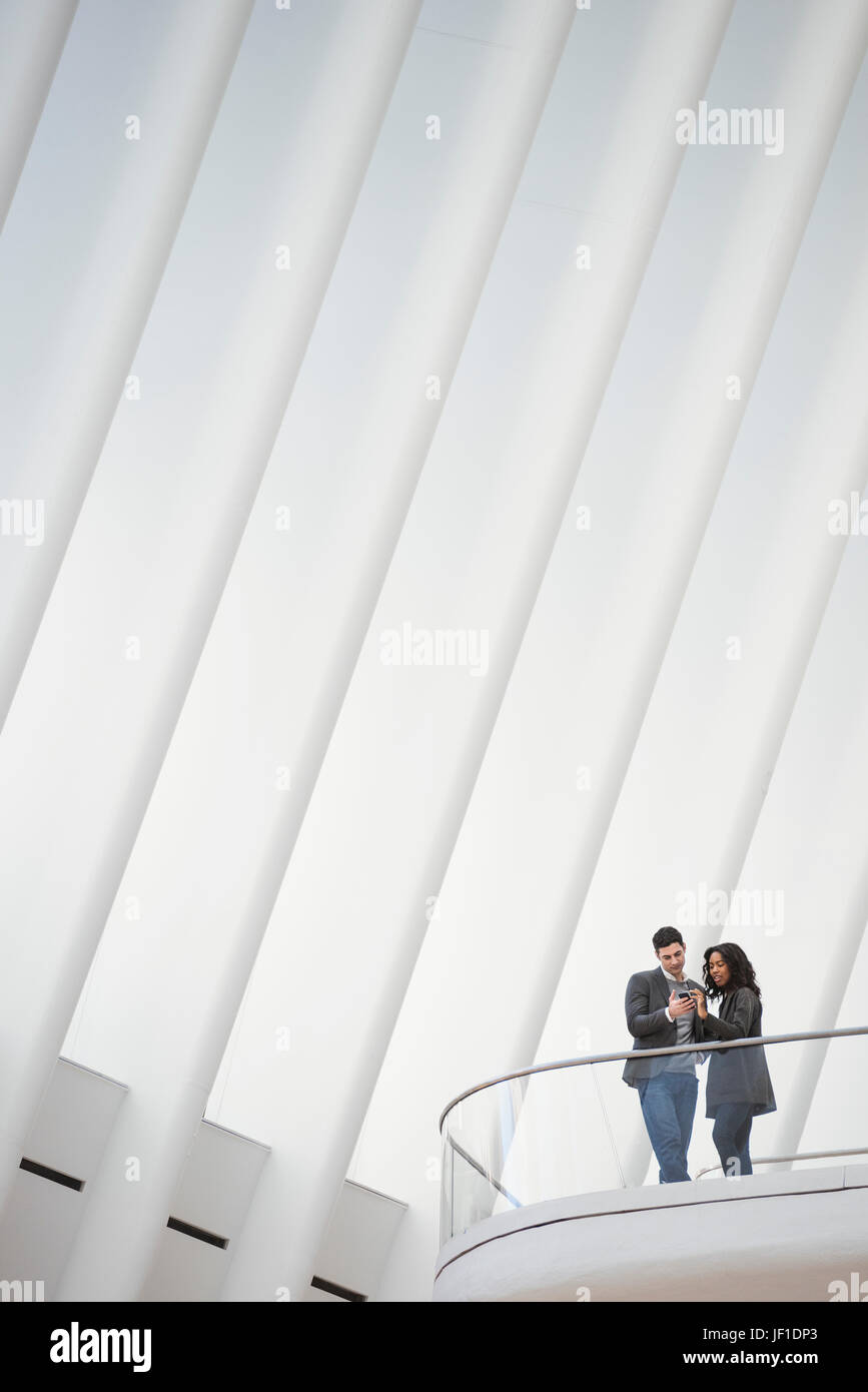 Blick von unten auf zwei Menschen stehen auf einem Balkon in das Oculus Gebäude, schwimmende Balkone über dem Boden im Dachraum. Stockfoto