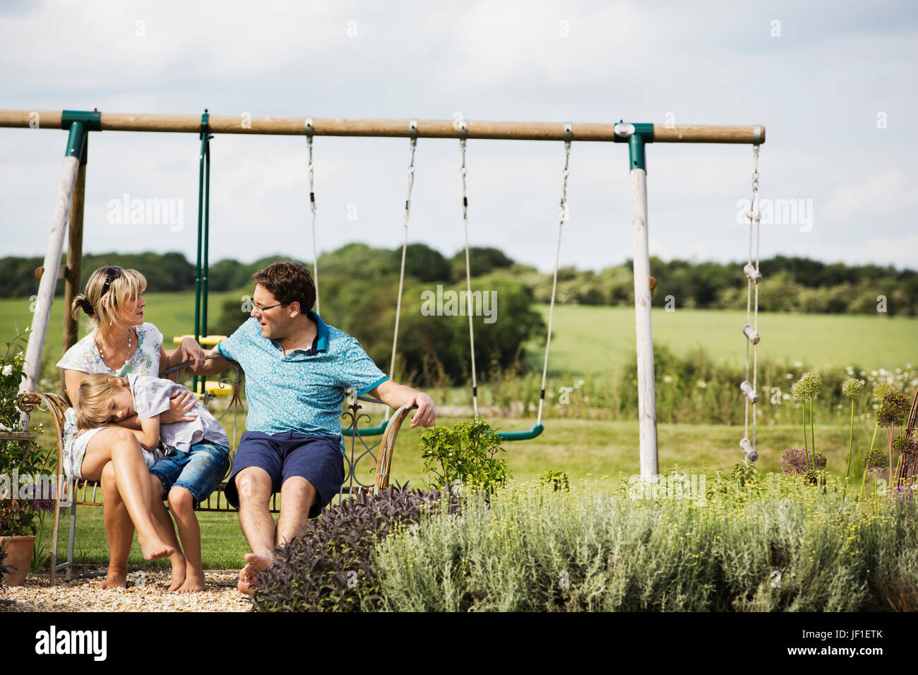 Mann, nebeneinander Frau und junge sitzt auf einer Schaukel im Garten. Stockfoto