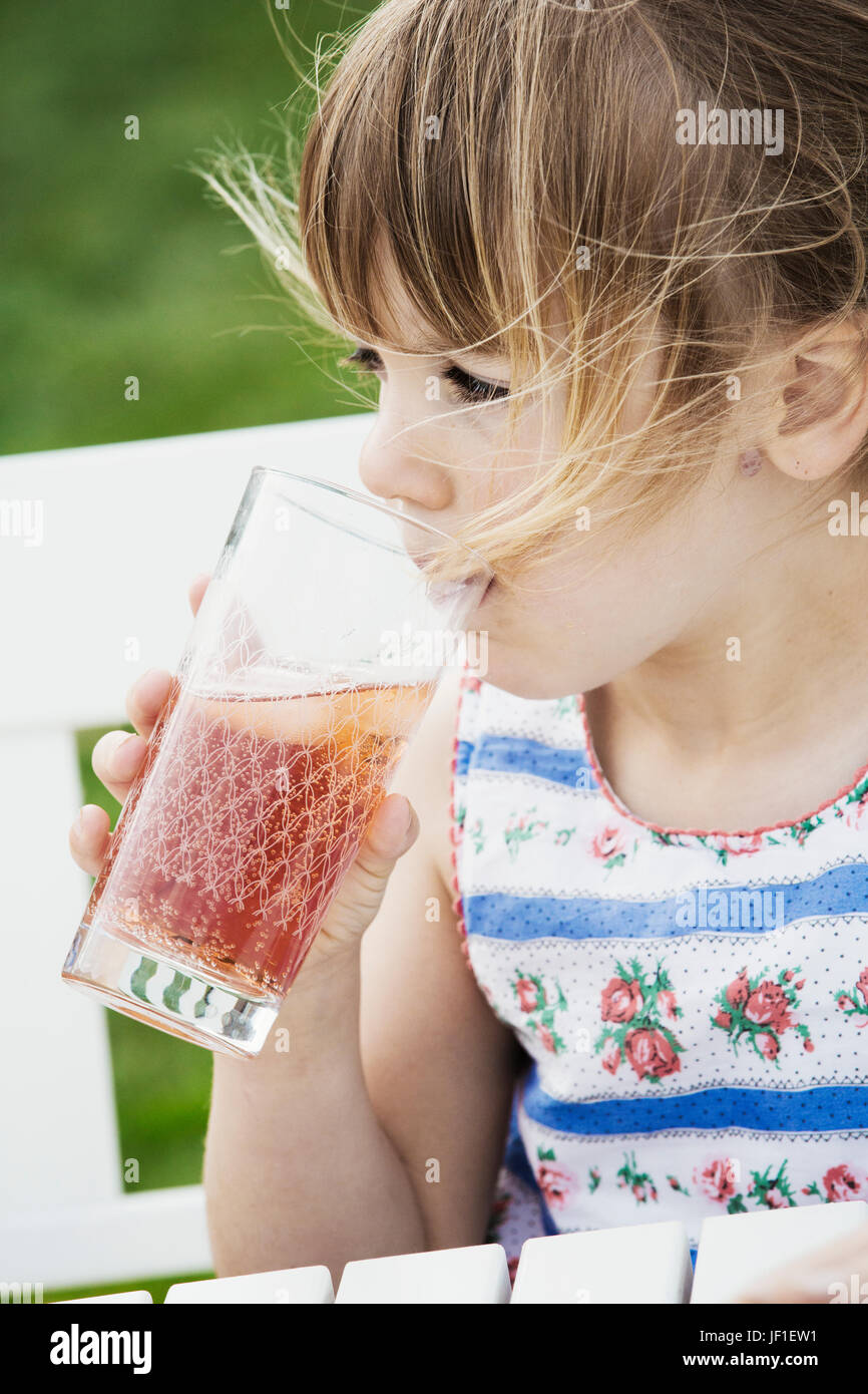 Mädchen sitzen draußen auf einer Bank aus einem Glas trinken. Stockfoto