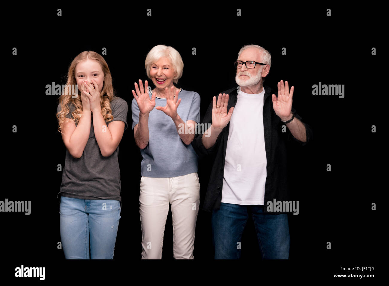 Senior Brautpaar stehend mit niedlichen Enkelkind und Spaß isoliert auf schwarz Stockfoto