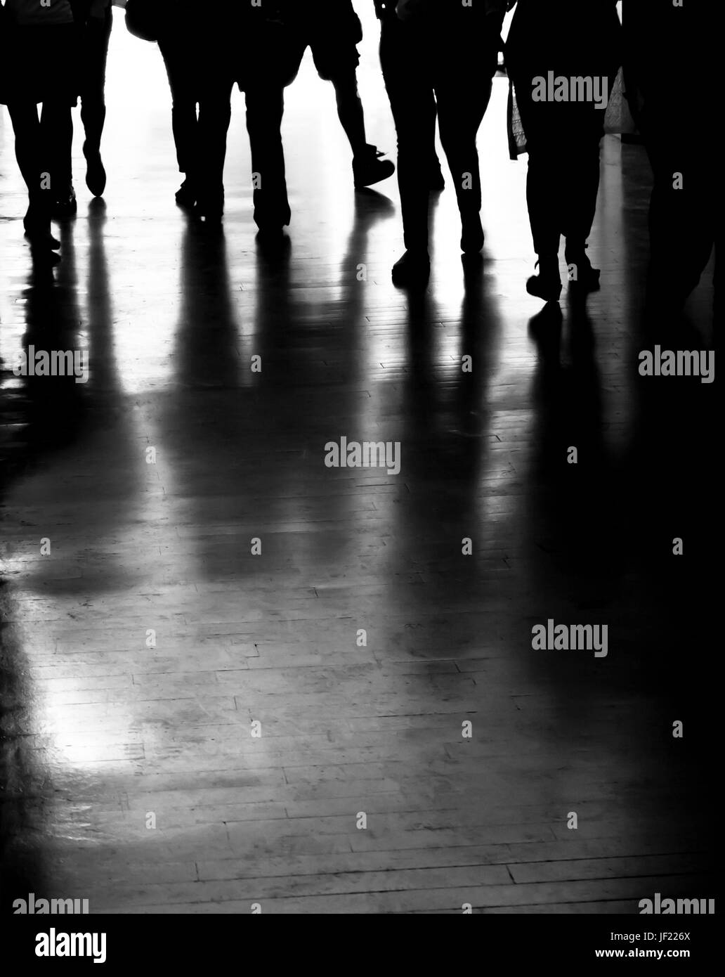 Gruppe von Menschen-Silhouetten und Schatten zu Fuß in die dunkle Stadt-Passage in schwarz / weiß Stockfoto