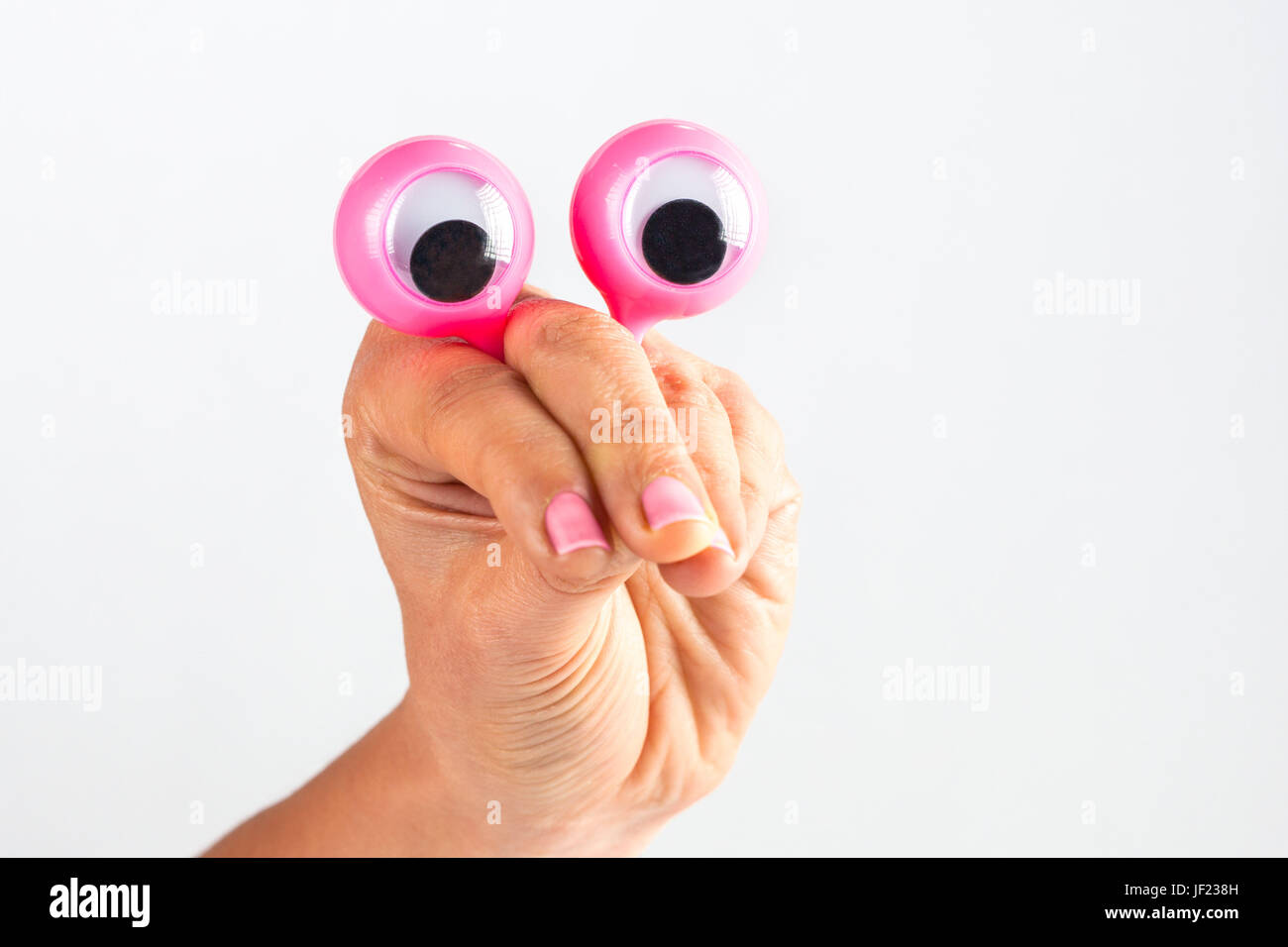 lustiger Charakter Kreatur suchen überrascht und verwirrt dargestellt mit weiblichen Hand und Googly Augen. Isoliert auf weiss mit Textfreiraum Stockfoto