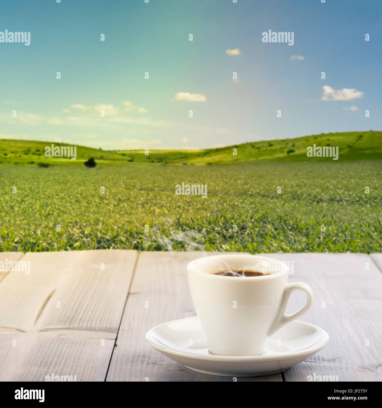 gedämpfte Tasse Kaffee auf Holztisch mit sonnige Landschaft im Hintergrund. Stockfoto