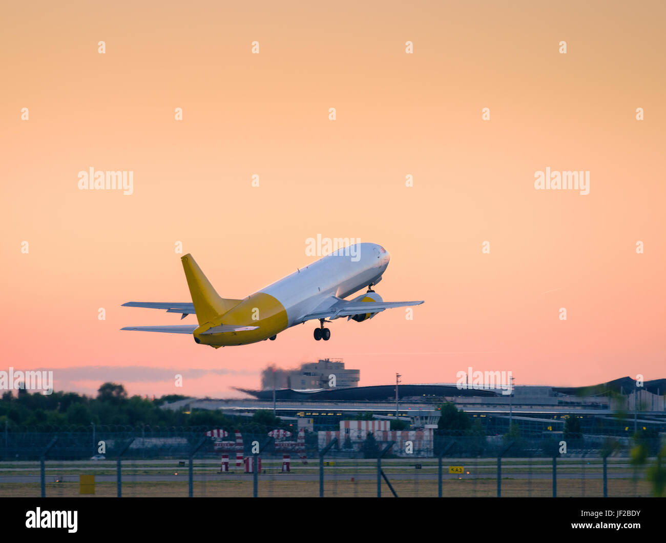 Flugzeug abheben bei Sonnenuntergang von der Startbahn. Industrielandschaft mit Frachtflugzeug ist am Abend in den orangefarbenen Himmel fliegen. Schöne Luft frei Stockfoto