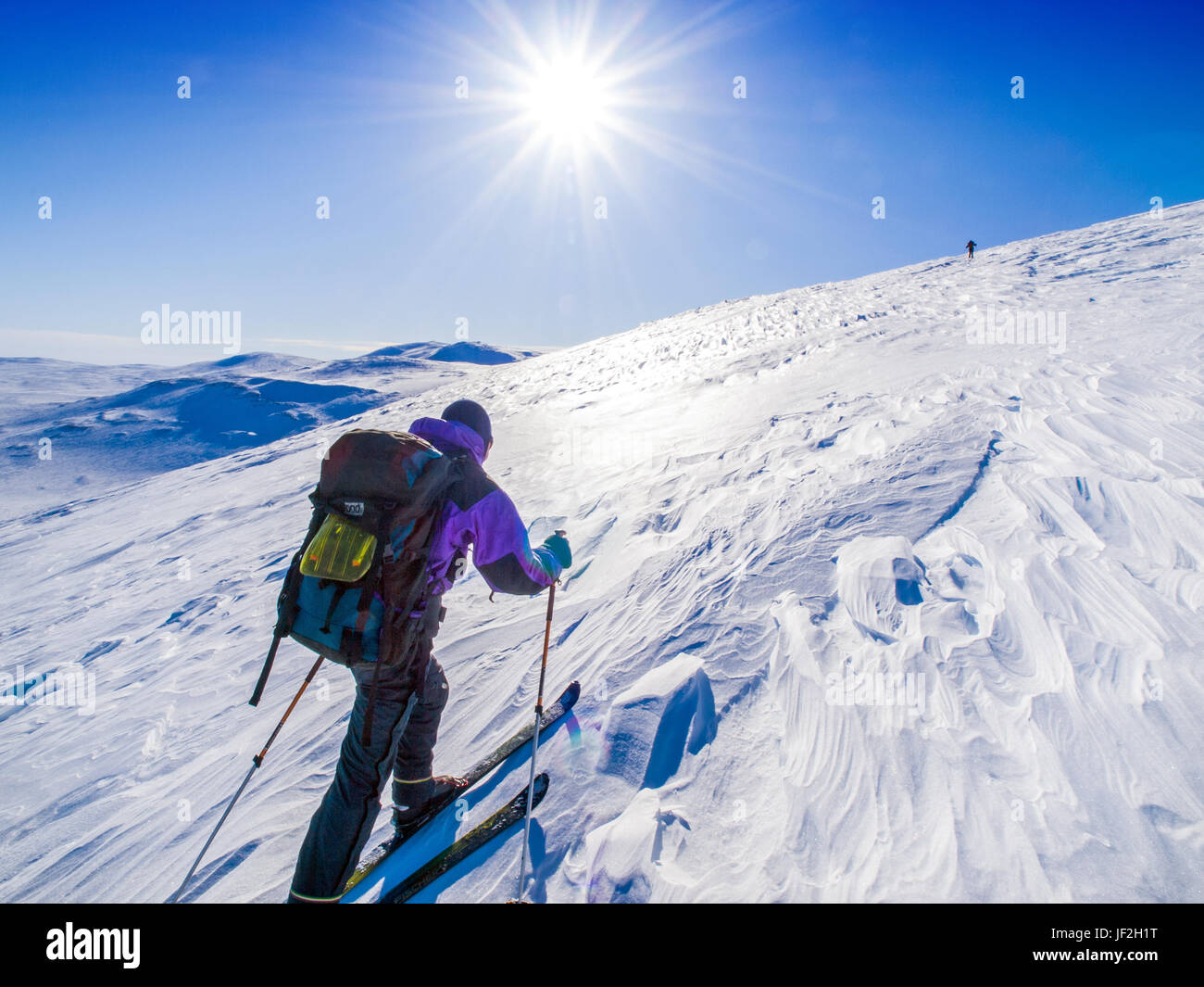Skitourengeher aufsteigender steilen Hang, in die Sonne, Finnland Stockfoto