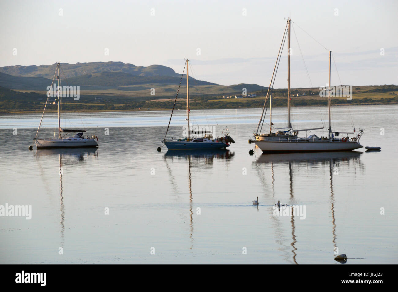 Vier Boote ankern in Merchiston, Small Isles Bay auf der Isle of Jura in den schottischen Inseln, Schottland, Vereinigtes Königreich. Stockfoto