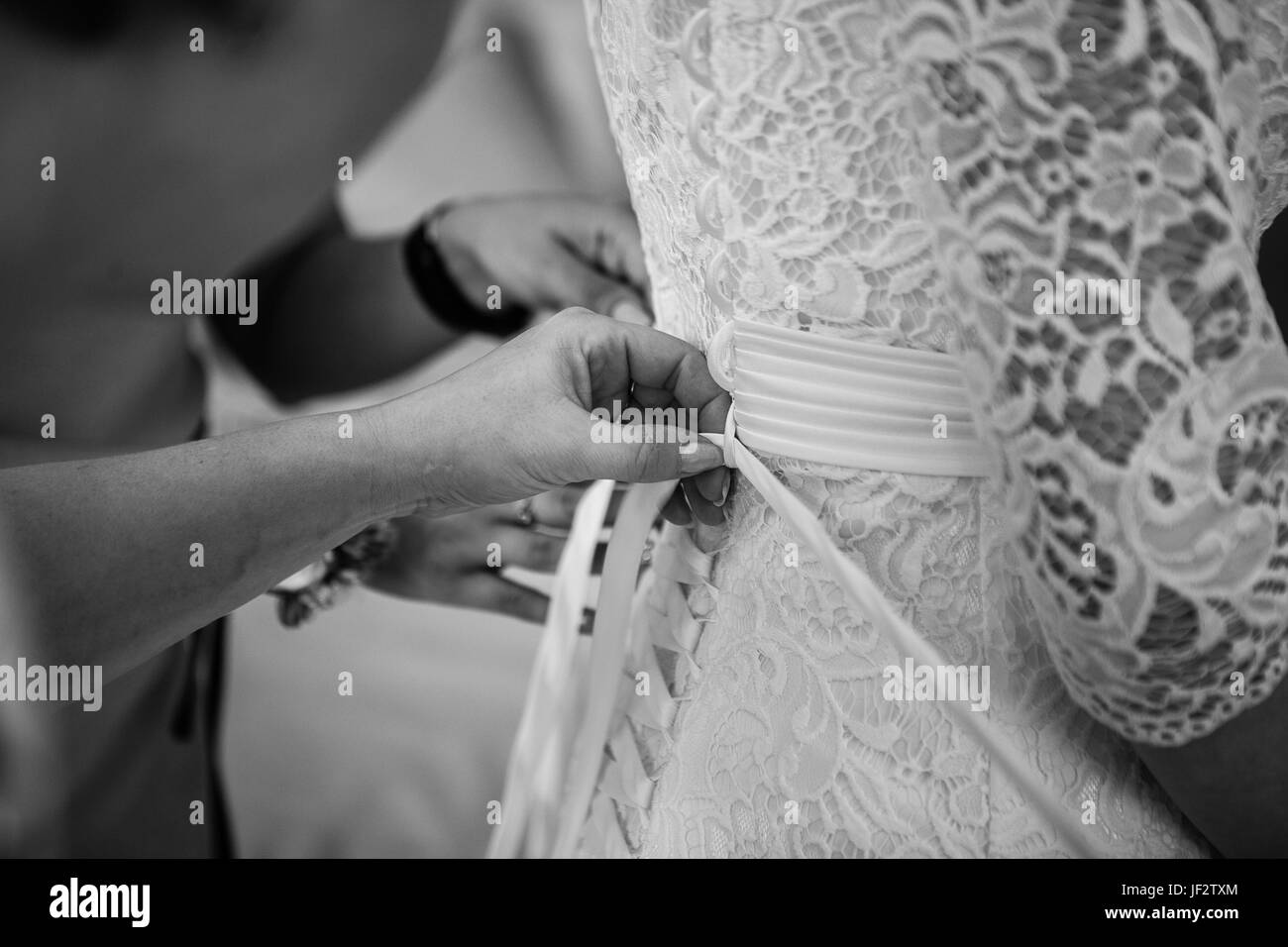 Brautjungfern helfen, setzen auf Krawatte Korsett Hochzeit Kleid Closeup b Mangel und weiß. Stockfoto